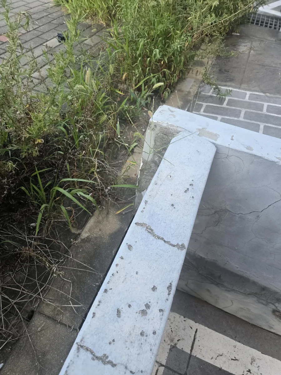 공장하자보수 견적 흰색 난간 하단 마감과 잡초가 자란 구간